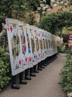 a row of playing cards sitting on the side of a road next to trees and flowers