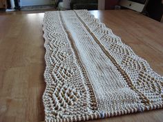 a knitted table runner sitting on top of a wooden table