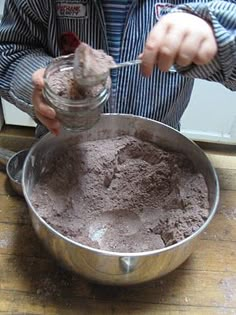 a person mixing something in a bowl on top of a wooden table with a spoon