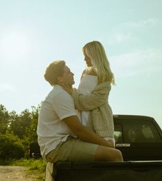 a man and woman sitting in the back of a pick up truck