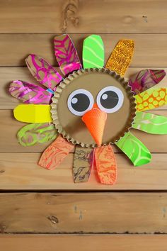 a paper plate turkey on a wooden surface