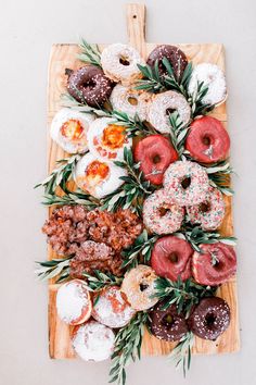 donuts and other pastries are arranged on a cutting board with sprigs