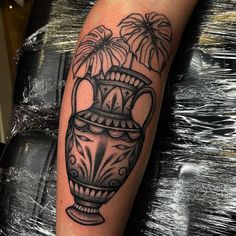 a black and white vase with flowers on it's arm, sitting on a table