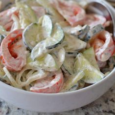 a white bowl filled with pasta and veggies on top of a marble counter