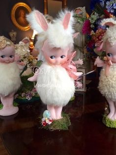 three little figurines that are sitting on a table with flowers in the background