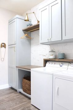 a washer and dryer in a room with white cabinets, wood flooring