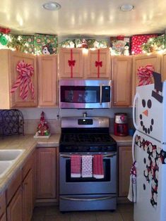 a kitchen decorated for christmas with snowman decorations on the cabinets, stove and refrigerator