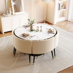 a living room filled with furniture and a round table surrounded by white rugs on top of a hard wood floor