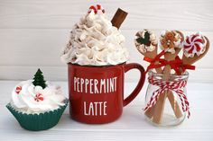 two mugs filled with marshmallows and candy canes are sitting next to each other