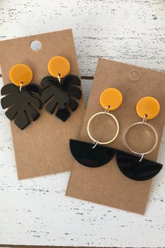 two pairs of black and yellow earrings on top of a piece of brown paper next to each other