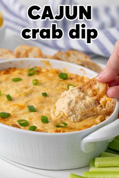 a hand dipping a cracker into a bowl of cajun crab dip