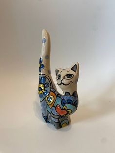 a ceramic cat figurine sitting on top of a white table next to a wall