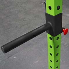 a close up of a green and black object with holes in the center, attached to a metal pole