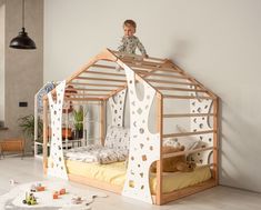 a little boy standing on top of a wooden house bed