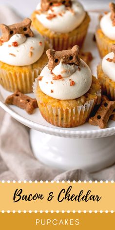 cupcakes with white frosting and dog decorations on top are sitting on a plate