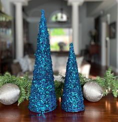 two blue christmas trees sitting on top of a wooden table