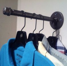 three shirts hanging on a rail in front of a wall with a coat hanger