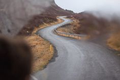 a curved road is seen through the windshield of a vehicle on a foggy day