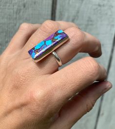 A stunning large rectangular cushion cut Kingsman turquoise has been set in sterling silver with a handmade ring band from sterling silver half dome wire. These stones are just stunning with varying patterns of interlacing colors of purple, blue, and copper. The stones have been set in a serrated setting for extra detailing. Made to order. Choose your stone by the correlating number above it in the last photo of the listing. Choose this number from the drop down menu titled stone. This is the ex Rectangular Cushion, Sterling Silver Rings Turquoise, Ring Turquoise, Turquoise Rings, December Birthstone, Half Dome, Ring Band, Boho Rings, Cushion Cut