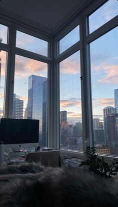 a living room filled with furniture and large windows overlooking the cityscape at sunset