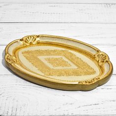 an ornately decorated gold tray on a white wooden surface