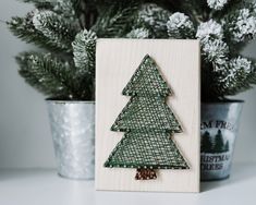 a small wooden christmas tree sitting next to a potted plant