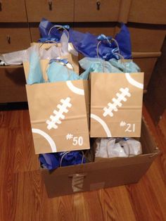 two brown paper bags filled with blue and white footballs sitting on top of a wooden floor