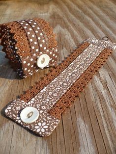 two pieces of brown and white lace with buttons on wooden floor next to each other