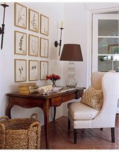 a living room with pictures on the wall and a chair next to a table in front of a window