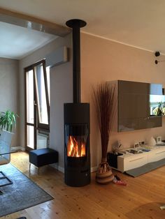 a living room with a wood burning stove in the center and furniture on the other side