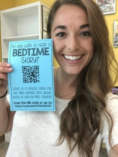 a woman holding up a bedtime story card with qr - code on it