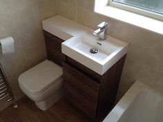 a white toilet sitting next to a sink in a bathroom under a window with light coming through the window