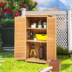 a wooden storage shed with gardening tools in the front and behind it, on green grass