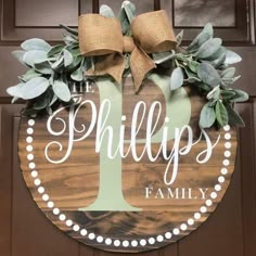 a wooden sign that says, the phillips family on it with a bow hanging from it's front door