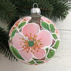 a pink flower ornament hanging from a christmas tree