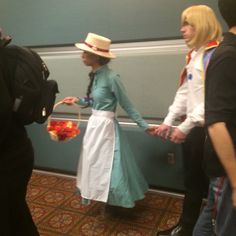 two people dressed in costumes standing next to each other near a wall with an open door