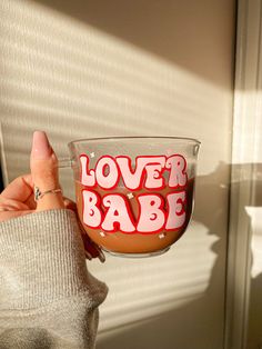 a person holding up a cup with the words lover babe on it