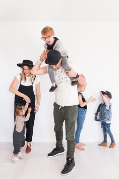 a group of people standing next to each other in front of a white wall and one person holding a child