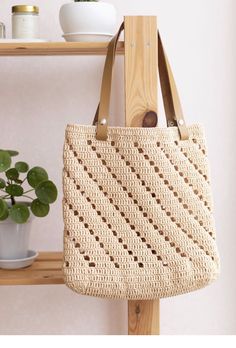 a handbag hanging on a wooden shelf next to a potted plant in a white room