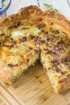 a quiche on a cutting board with one slice missing