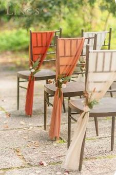 chairs with orange sashes are lined up on the ground for an outdoor wedding ceremony