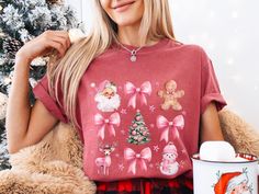 Spread some holiday cheer with this adorable pink Christmas T-shirt. Featuring a charming watercolor design of Santa Claus, bows, a gingerbread man, a Christmas tree, a reindeer, and a snowman, this shirt is perfect for the festive season. This shirt is stylish and cozy and made from soft and comfortable Comfort Colors 1717 fabric. Pink Christmas design Watercolor style Comfort Colors 1717 fabric Soft and comfortable Perfect for the holidays Are you looking for a unique Christmas t-shirt? Look n Cute Pink Holiday Tops, Cute Pink Holiday Top, Cute Pink Top For Holiday, Cute Pink Christmas Tops, Cute Pink Christmas T-shirt, Pink Coquette Christmas, Coquette Shirt, Coquette Christmas, Christmas Pink