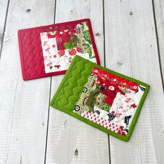 two quilted placemats sitting on top of a white wooden table next to each other