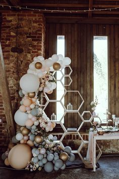 a room filled with balloons and flowers next to a table in front of two windows