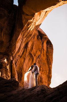 a bride and groom standing in front of a rock formation at the end of their wedding day