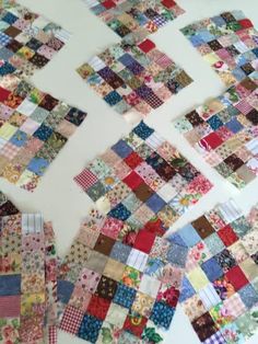 several pieces of colorful fabric laid out on a white table with one piece missing from the quilt