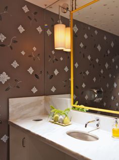 a bathroom with a sink, mirror and wallpaper in the background that has flowers on it