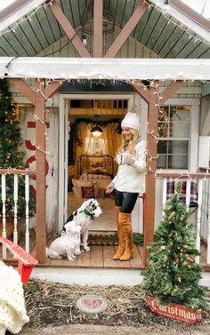 a woman standing in the doorway of a house with her dog and christmas decorations on the porch