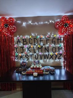 a table topped with lots of food next to a wall covered in letters and balloons