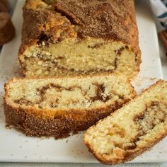 a loaf of cinnamon swirl bread cut into slices on a white cutting board next to an apple and cinnamon muffin